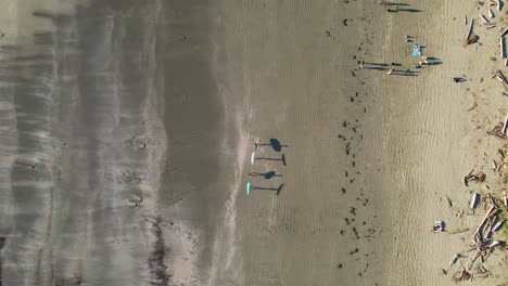 Freunde-Gehen-Mit-Surfbrettern-Am-Strand-Spazieren,-Die-Schatten-Werfen