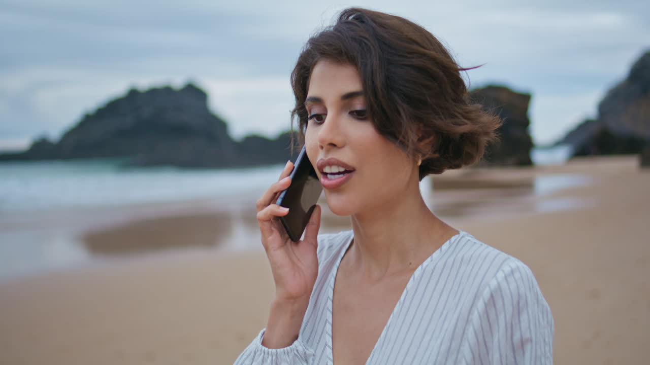 Attractive woman talking mobile phone at shore closeup. Beach lady making call
