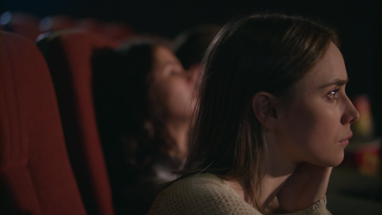 chica joven mirando pensativa película en el cine. cara de mujer bonita en el cine