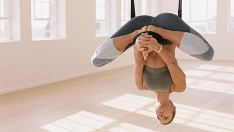 aerial yoga woman practicing inverted lotus pose hanging upside down using hammock enjoying healthy fitness lifestyle exercising in studio training meditation at sunrise