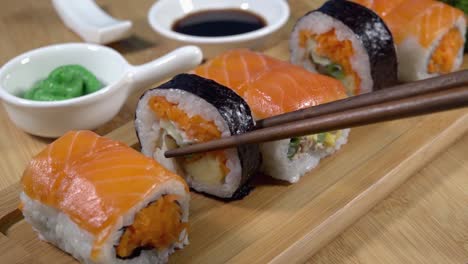 recogiendo sushi de una tabla de servir de bambú con palillos