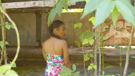 a model sits in the window of an abandoned warehouse with grafitti art in the background