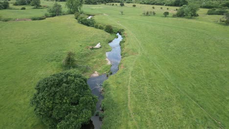 An-aerial-view-of-the-tiny-river-Arrow-as-it-twists-it's-way-through-the-Warwickshire-countryside,-England