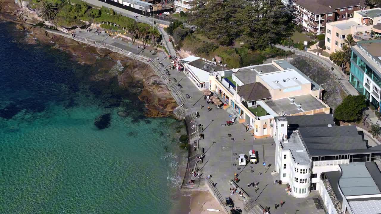 Drone of Cronulla headland, coastline, buildings and blue sea under clear sky, establishing of promenade, Sydney NSW Australia