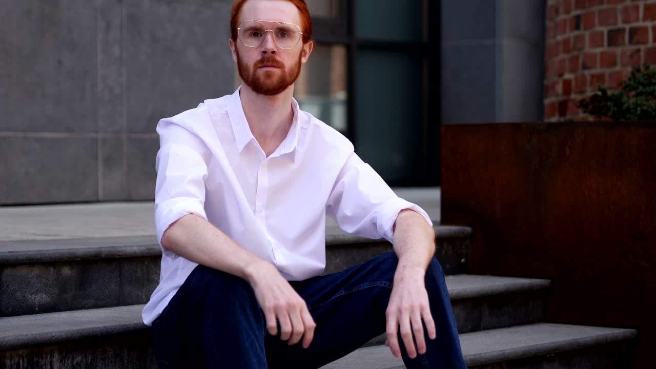 pulgares hacia arriba por el diseñador sentado en las escaleras de la oficina