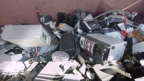 slider, slomo, electronics being thrown into a huge bin at a recycling centre