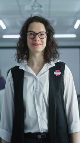 woman in camouflage uniform stands in polling station and looks at camera. portrait of female soldier, united states of america elections voter. background with voting booths. concept of civic duty.