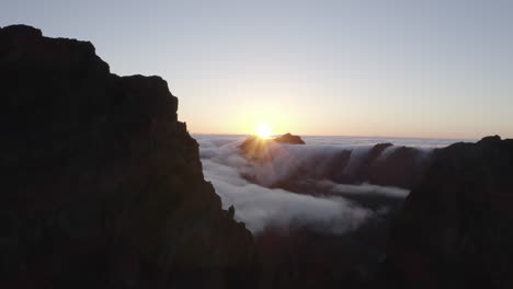 drone aerial footage flying past mountain peaks towards rolling clouds over a mountain on maderia island, portugal