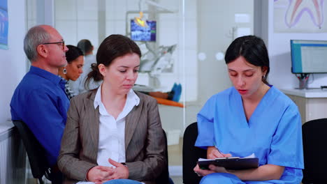 enfermera tomando notas en el clipboard sobre los problemas dentales del paciente