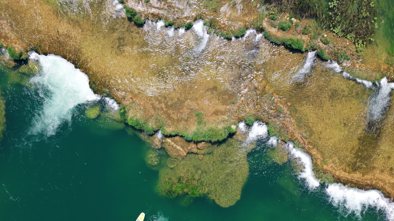 Pristine Waterfalls And A Person Swimming With A Paddleboard In Mrežnica River, Croatia. Aerial Topdown Shot