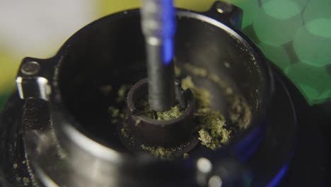 close up of using a probe to pack marijuana into the bowl of a vaporizer used for smoking pot or medical marijuana