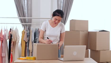 young online store owner packing delivery into cardboard box in home