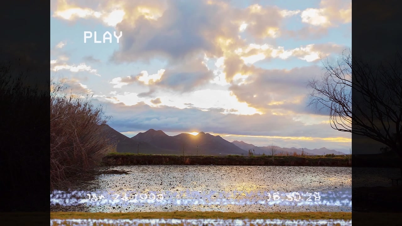 Animation of glitch technique on screen with time-lapse of moving clouds over lake and mountains