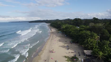 aerial pullback of the scenic punta cocles coastline in puerto viejo, costa rica with tourists relaxing on beach
