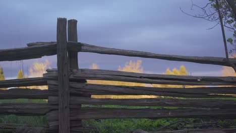 rustic wooden farm fence at sunset, trees backlit in background