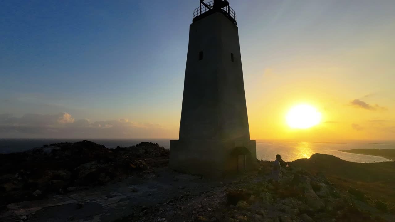 Time Lapse people hiking to the top of a hill to watch the sunrise at the lighthouse overlooking the Caribbean Sea in Los Roques, Venezuela.