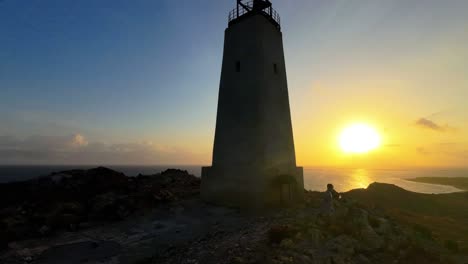 time lapse people hiking to the top of a hill to watch the sunrise at the lighthouse overlooking the caribbean sea in los roques, venezuela.