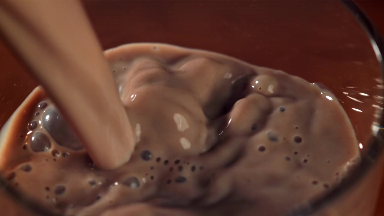 Versamento al rallentatore di latte al cioccolato in un bicchiere