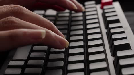 dedos escribiendo en el teclado mecánico gris de la computadora, disparo de cerca a un lado