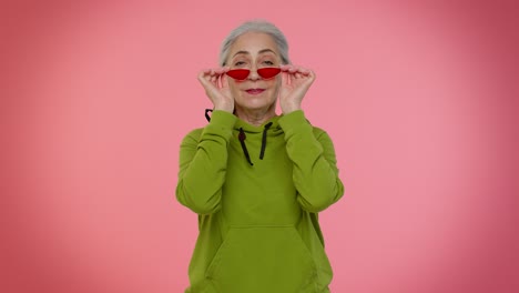 feliz juguetona anciana elegante abuela mujer con gafas de sol parpadeando el ojo, mirando a la cámara con una sonrisa
