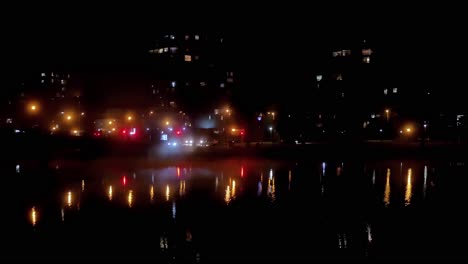 night lights reflect over lagoon with mist rolling in from the bridge's side