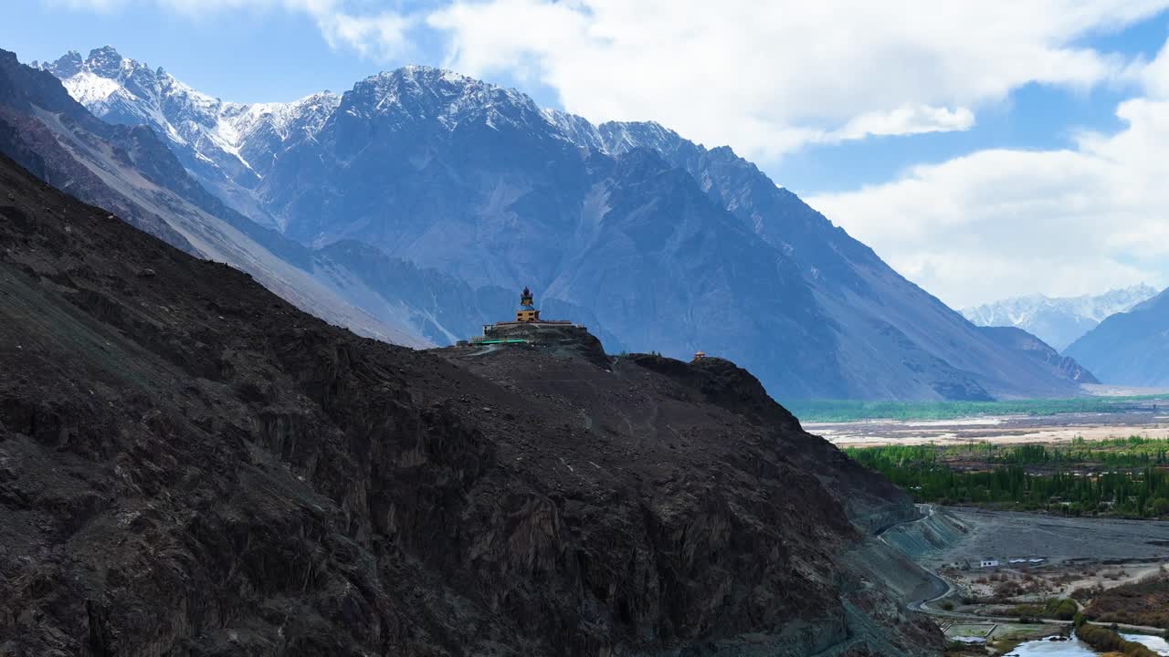 Aerial drone shot capturing the historic Diskit Monastery with its colorful prayer flags fluttering against mountain backdrops.