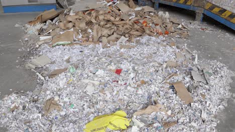 Stack-of-shredded-paper-waste-on-concrete-floor-of-recycling-plant