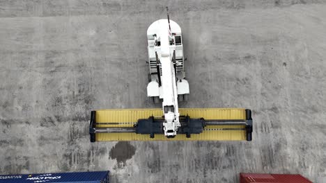 overhead drone shot of a heavy duty container handler reversing, moving a container