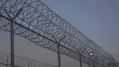 pan along prison razor wire at sunset outside jail 4k