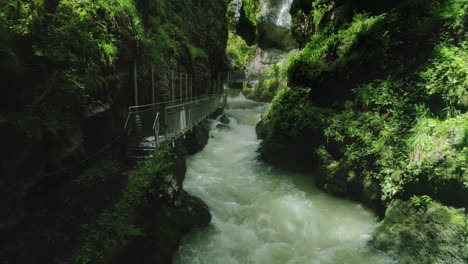 Drohnenwagen-In-Einem-Turbulenten-Fluss-In-Einer-Engen-Schlucht-Mit-Gehweg