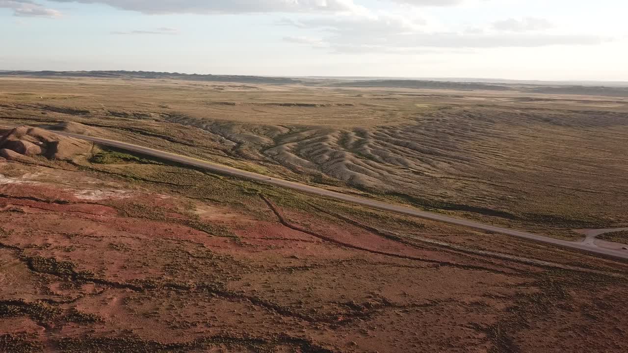 antena cinematográfica en un vehículo solitario en la carretera a través del pintoresco paisaje del desierto de wyoming, amplio panorama