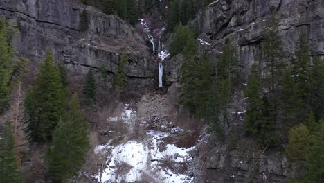 frozen waterfall surrounded by evergreens and open cliff faces