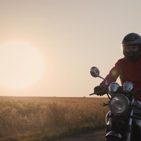 a silhueta de um motociclista andando em uma estrada rural ao pôr do sol