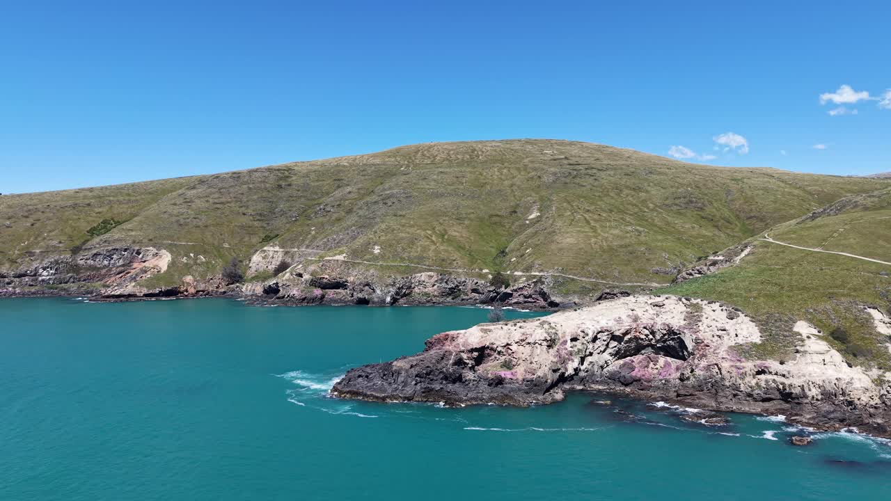 Flying past finger of land to reveal secluded bay and walkway in distance (Godley Head Walkway, Canterbury, New Zealand)