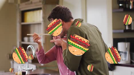 Multiple-burger-icons-falling-against-mixed-race-couple-tasting-food-in-the-kitchen-at-home