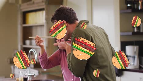 multiple burger icons falling against mixed race couple tasting food in the kitchen at home