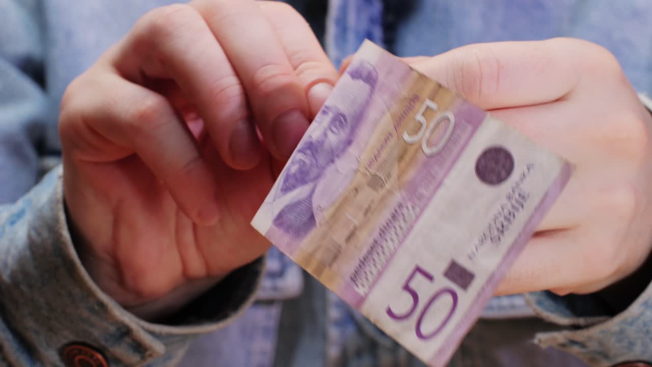 A person carefully holding a 50 peso bill, effectively showcasing its unique design and vital importance in commerce