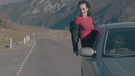 confident young lady in black jacket leans out of car window