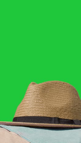 video vacaciones de verano vertical concepto de sombrero de sol teléfono móvil toalla de playa en la arena contra la pantalla verde