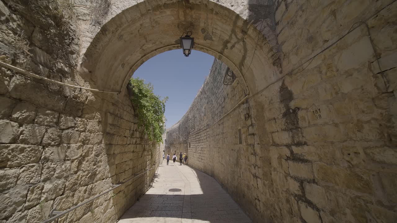 Folk går gennem stenbuegang inden for Vestmuren i Jerusalems gamle bydel i Israel.