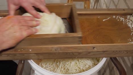 Grate-cabbage-with-old-wooden-grater-for-sauerkraut,-static-side-close-up