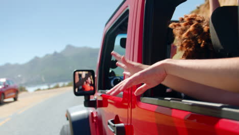 grupo de amigas riendo saludando a través de las ventanas laterales de un coche abierto en un viaje por carretera