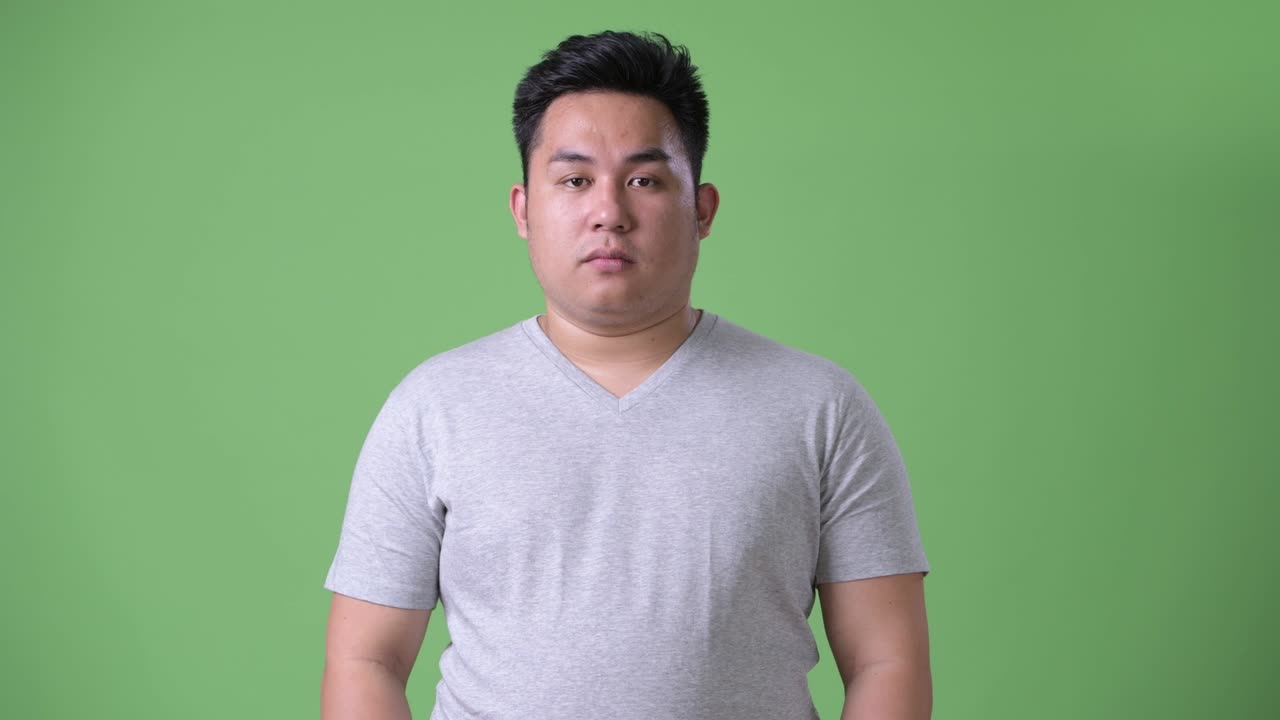 초록색 배경에 젊은 잘생긴 과체중 아시아인