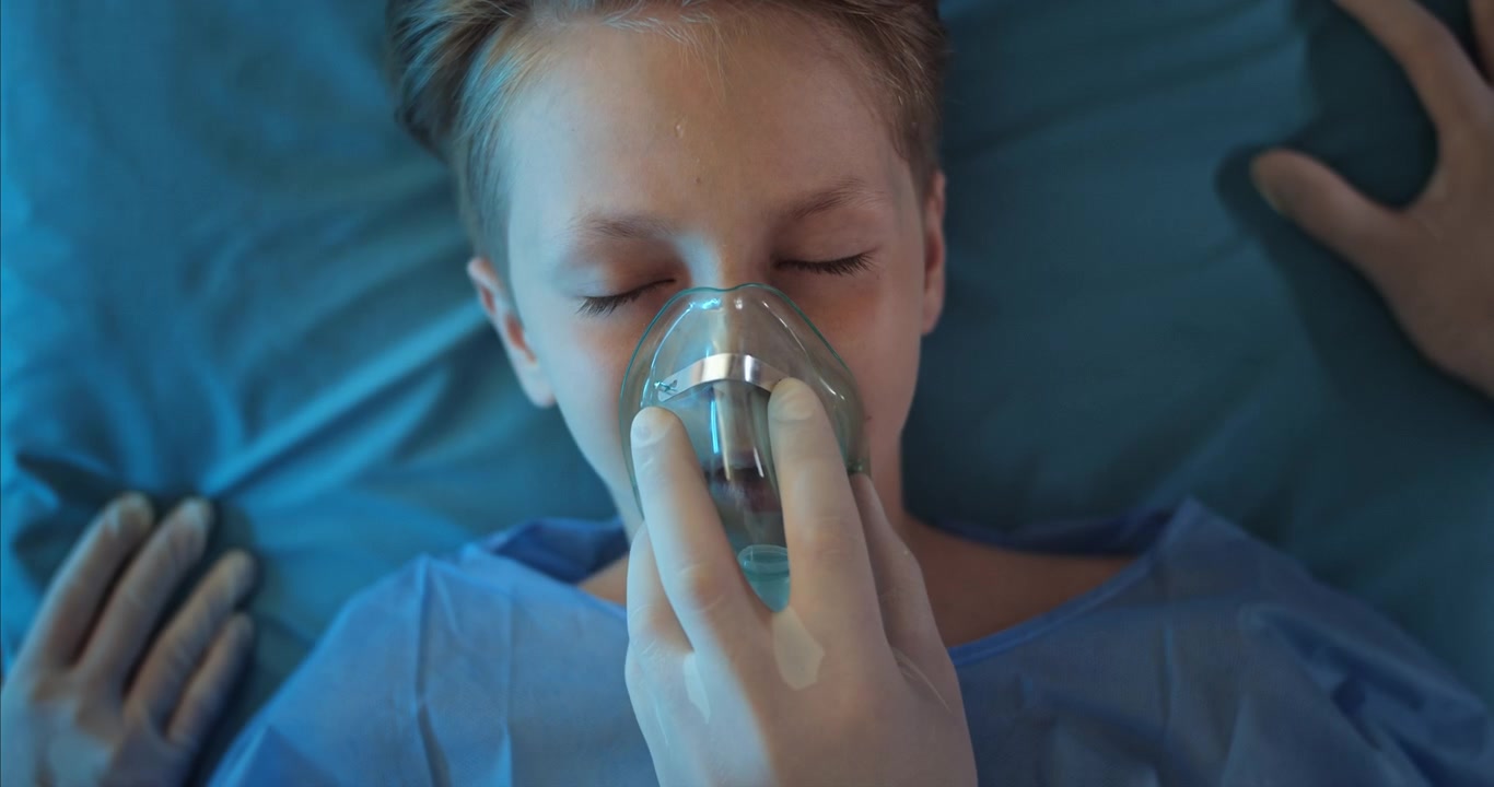Professionista medico somministra maschera per l'ossigeno a un giovane paziente bambino