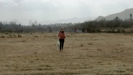 chinese woman running through rural farmland field towards drone, pull-back view