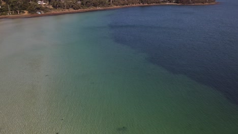 Panorámica-Aérea-De-Drones-Sobre-Aguas-Azules-Tropicales-Para-Mostrar-Casas-En-Frente-De-La-Playa-De-Arena