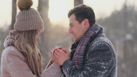 a couple in love a man warms his hands with his breath a woman. stylish couple in the park in winter for a walk.