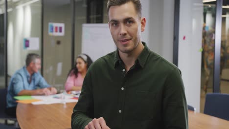 retrato de un feliz hombre de negocios caucásico usando una tableta y mirando a la cámara en la oficina