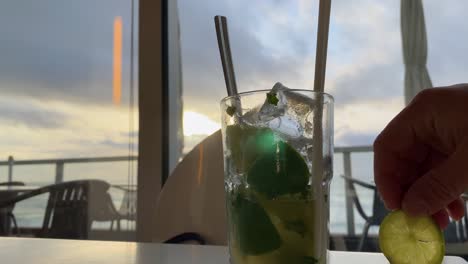 Enhance-the-tropical-flavors-of-a-sunset-mojito-with-a-zesty-twist-of-fresh-lemon,-while-taking-in-the-breathtaking-ocean-view