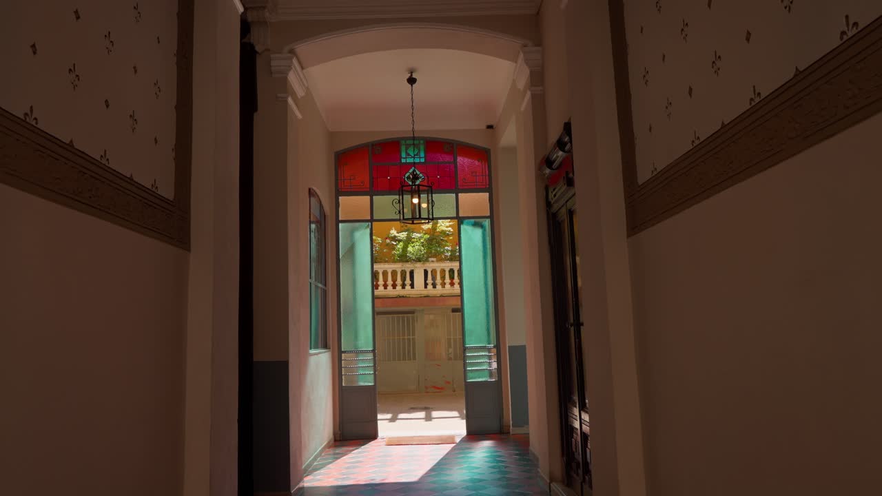Slow push-in shot of an internal courtyard in a Milanese-style building with elegant architecture and vibrant stained glass windows in Milan Milano Italy